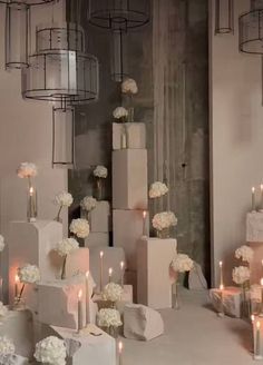 a table topped with lots of white flowers next to tall vases filled with candles