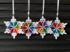 three colorful paper flowers hanging from strings on a wooden surface with string attached to them