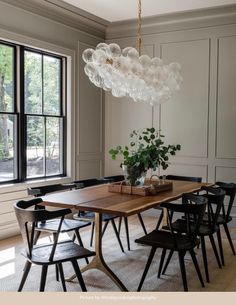 a dining room table with black chairs and a wooden table surrounded by glass globes