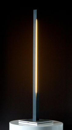 a light that is sitting on top of a white pedestal with a black base and two yellow sticks sticking out of it