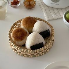 three pastries sitting in a basket on a table next to bowls of fruit and yogurt