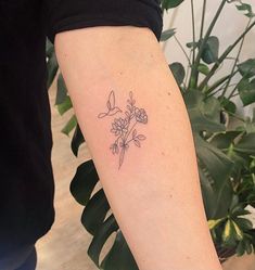 a woman's arm with a small flower tattoo on the left side of her right arm