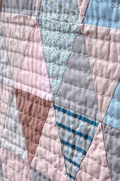 a quilted wall hanging with several different colored triangles on it's sides,