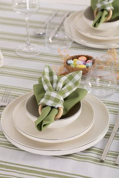 the table is set with plates, silverware and green napkins on top of them