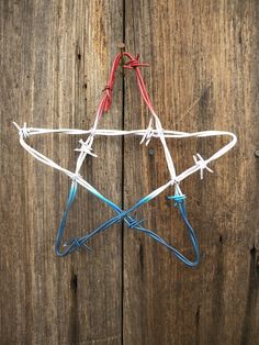 a wire star ornament hanging from a wooden fence