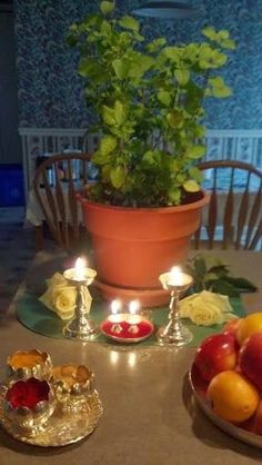 a table topped with fruit and candles on top of a wooden table next to a potted plant