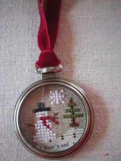 a cross stitch christmas ornament hanging from a red ribbon