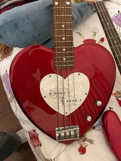 a red heart shaped guitar laying on top of a bed