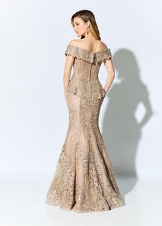 a woman in an off the shoulder dress with gold sequins and lace on it