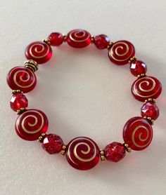 "Beautiful holiday red Czech glass spiral beads and ruby red shimmering Picasso glass with antique gold accents on a stretch bracelet. Matte red and gold puffy spiral coin beads are 12 x 14 mm with translucent Picasso glaze. Alternating 8 mm ruby red beads with gold Picasso finish. Lovely beads are accented with antique gold plated daisies and beaded spacers by Tierracast made in USA. Made to order in your size. Bracelet is made on professional stretch elastic. Example is about 7\" and fits a 6\ Red Czech Glass Bracelet, Gold Stretch Bracelet, Handmade Jewlery, Red Bracelet, Bracelet Christmas, Diy Jewelry Unique, Ball Bracelet, Dope Jewelry, Spiral Earrings