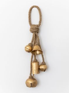 three bells hanging from a rope on a white wall