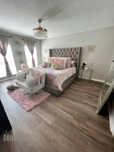 a bedroom with hardwood floors and pink bedding in the center, along with a staircase leading up to it