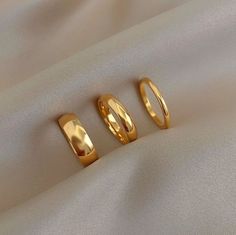 three gold rings laying on top of a white cloth