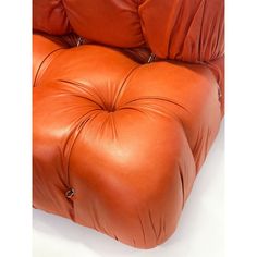 an orange leather chair with two pillows on it's back and the seat upholstered