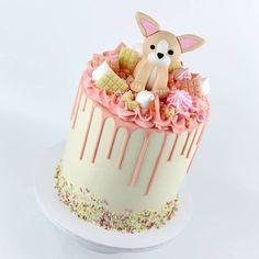 there is a cake decorated with pink icing and a dog sitting on top of it