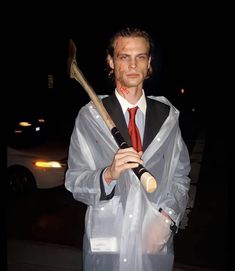 a man dressed up as a zombie holding a large hammer and wearing a plastic coat