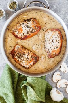 some food is in a pan on a table next to garlic and seasoning sprinkles