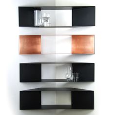 three black and white shelves with glass vases on each shelf, against a white wall