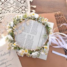 a wedding wreath on top of an open book next to a lace doily and ribbon