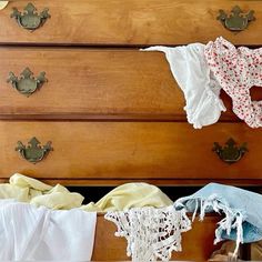 an old dresser with clothes hanging on it