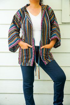 Introducing our Unisex Hand Woven Cotton Hippie Cardigan with Hood and Pockets, a versatile and stylish addition to your boho wardrobe. Perfect for both men and women, this cardigan is designed to offer comfort, practicality, and a touch of hippie charm. Crafted with natural cotton fibers, each piece is meticulously hand-woven with love and care, ensuring a unique and natural look. Key Features * Material: Natural Cotton Fibers: Made from 100% pure cotton, this cardigan is soft, breathable, and non-transparent, providing ultimate comfort for all-day wear. * Design :Hood with Adjustable Rope and Coconut Caps: The decorative hood features an adjustable rope adorned with coconut caps, enhancing the hippie aesthetic. * Front Ties: Simple front ties add to the cardigan's boho charm while allowi Decorative Hood, Hippie Cardigan, Boho Wardrobe, Cardigan With Hood, Hippie Clothing, Hippie Aesthetic, The Cardigans, Poncho Cardigan, Cover Ups