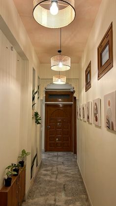 a long hallway with pictures on the wall and a light fixture hanging from the ceiling