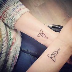 two people with matching tattoos on their arms, one is holding the other's hand