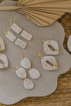 some white and gold earrings are on a gray tray next to an umbrella, with other items in the background