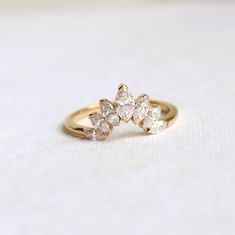 a yellow gold ring with three pear shaped diamonds on the top and bottom, sitting on a white surface