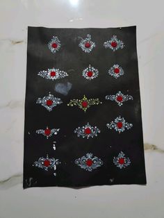 an embroidered black cloth with red and white designs on it, sitting on a marble surface