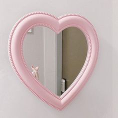 a pink heart shaped mirror hanging on the wall