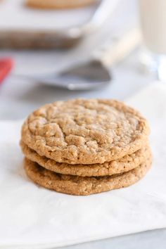 three cookies stacked on top of each other with a glass of milk in the background