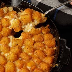 a skillet with some tater tots in it and someone holding a spoon