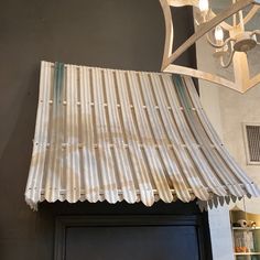 a light fixture hanging from the ceiling above a door with a tin roof and metal slats on it