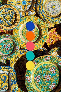 many colorful plates are stacked on top of each other with circles and flowers painted on them