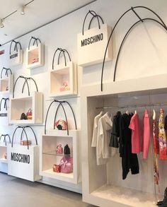 the inside of a clothing store with clothes on shelves and bags hanging from the ceiling