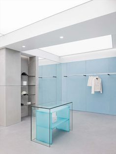 an empty room with blue glass shelves and clothes hanging on the rack in front of it