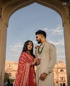 a man and woman standing next to each other in front of a building with arches