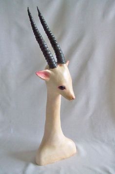 a ceramic deer head with long horns on it's head, against a white background