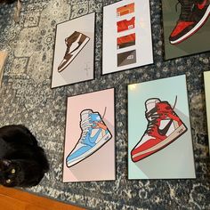 a black cat laying on the floor next to some pictures and shoes in front of it