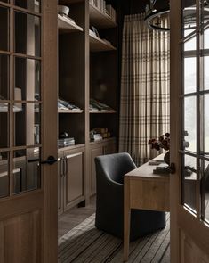 an open door leading to a living room and dining area with wooden shelves on the wall