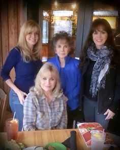 three women standing next to each other at a table