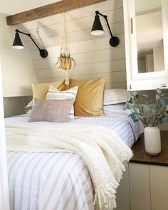 a bed with two lamps on the wall above it and a white striped bedspread