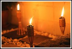 two lit candles sitting on top of a table next to rocks and pebbles in front of a wall