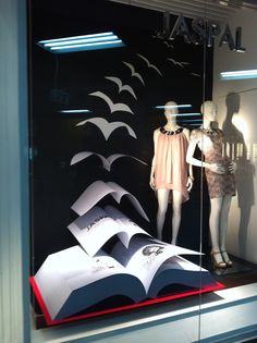 two mannequins and an open book in a window