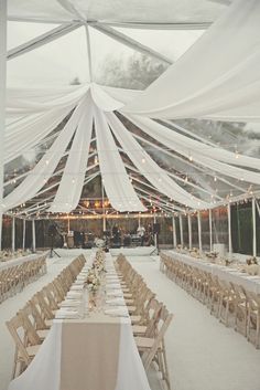 the inside of a tent with tables and chairs set up for an outdoor wedding reception