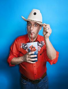 a man wearing a straw hat and holding a drink in front of his face while making a funny face