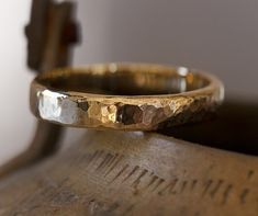 a close up of a gold ring on top of a wooden object with a cross in the background