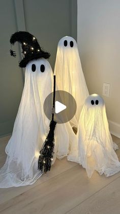 three white ghost decorations with lights on them