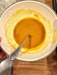 a person holding a spoon in a bowl of food